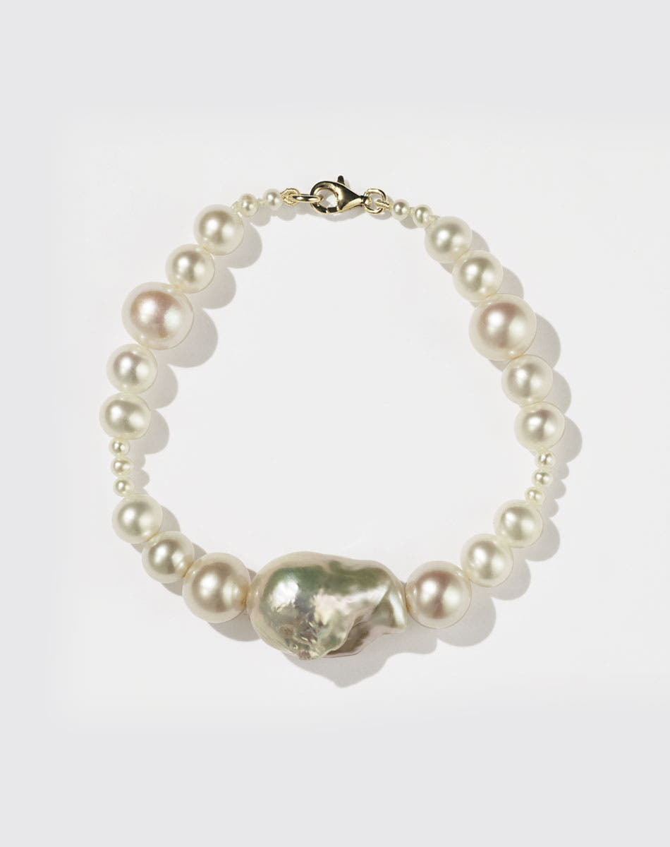 A pearl bracelet featuring a string of round and baroque pearls with a gold clasp.
