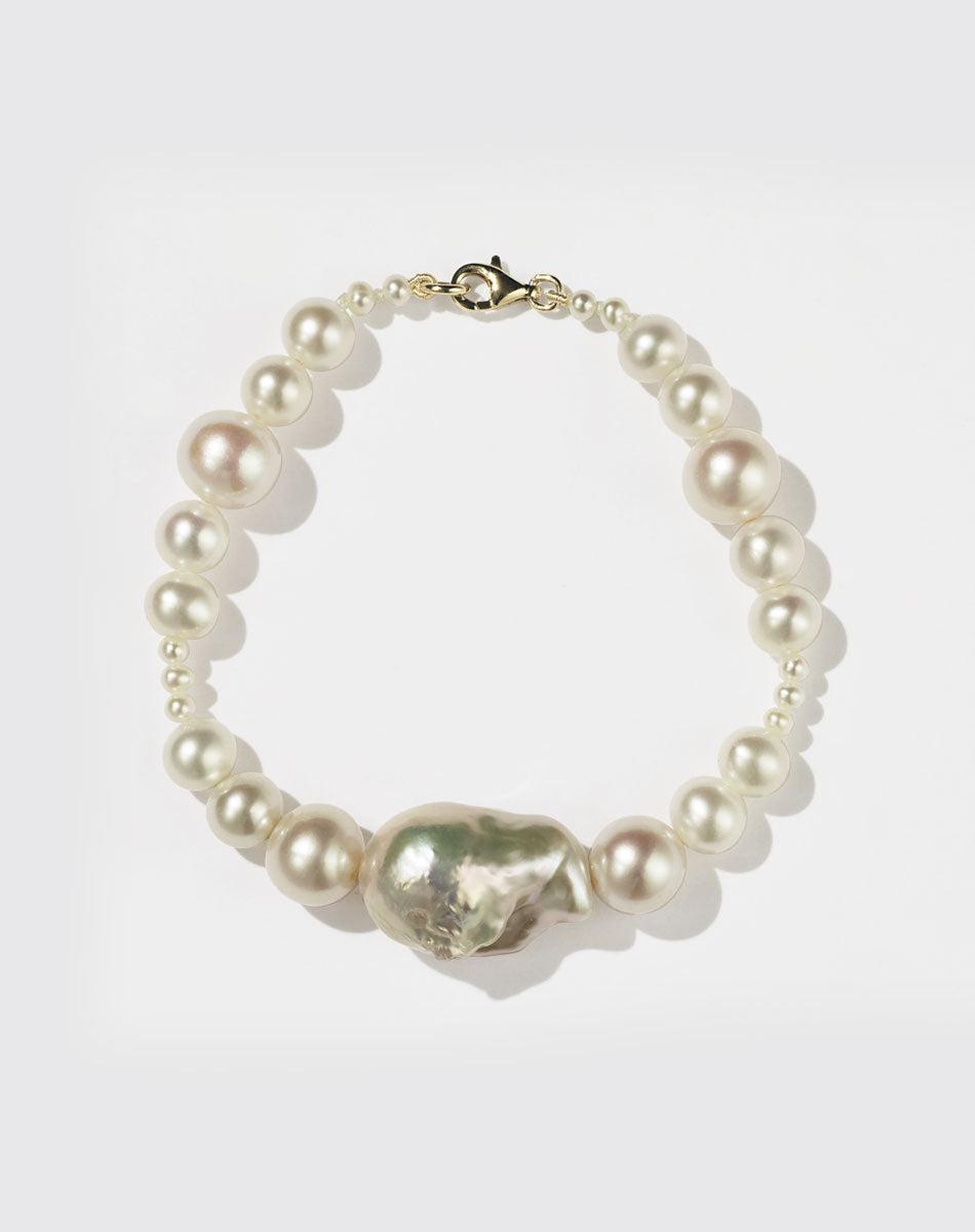 A pearl bracelet featuring a string of round and baroque pearls with a gold clasp.