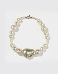 A pearl bracelet featuring a string of round and baroque pearls with a gold clasp.