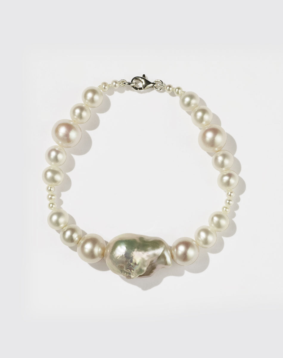 A sterling silver bracelet featuring a string of round and baroque pearls with a silver clasp.