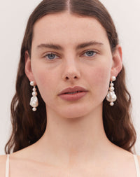 Pearl drop earrings featuring a series of round and baroque pearls worn on a model