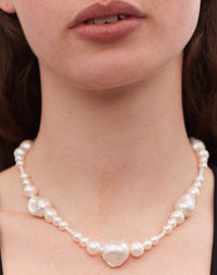 A necklace featuring a strand of round and baroque freshwater pearls worn on a model.