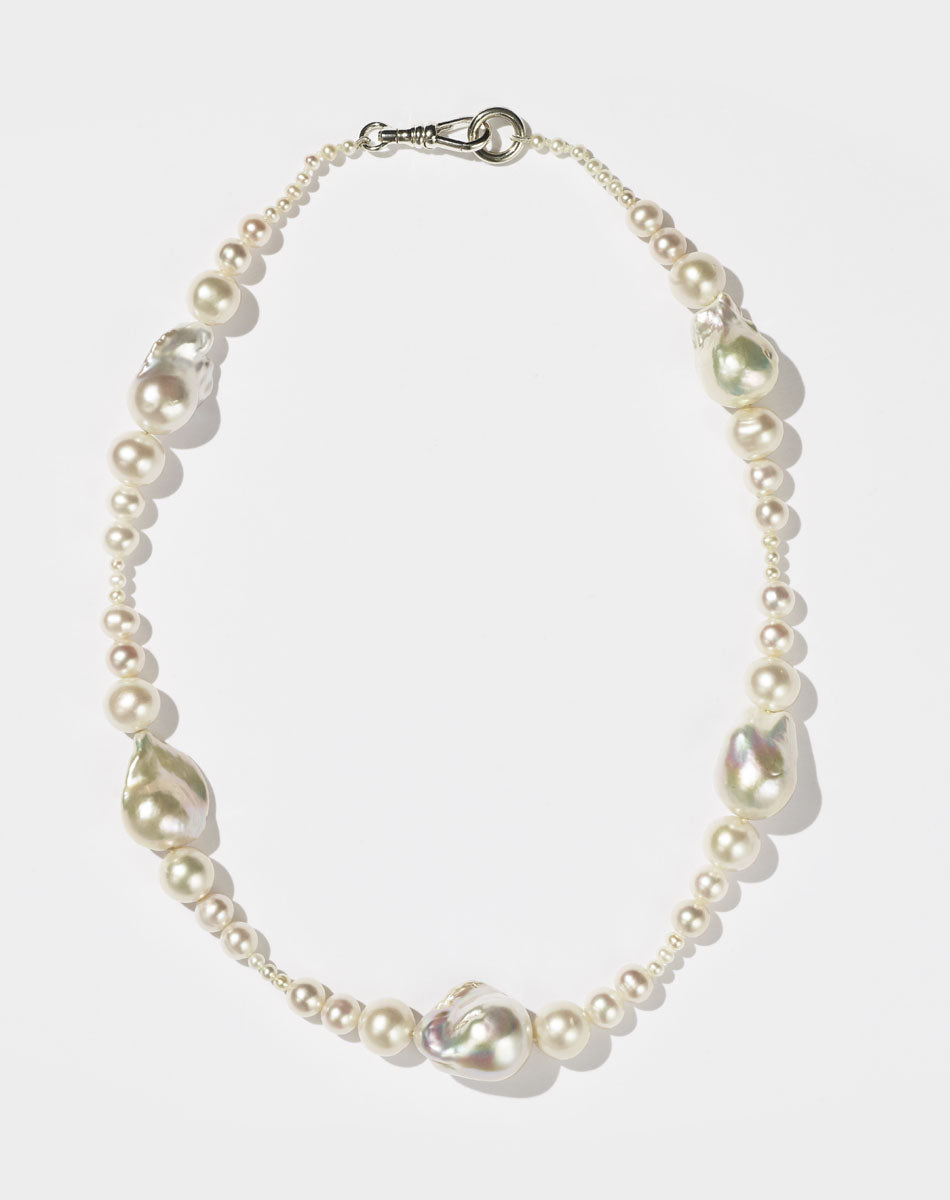 A sterling silver necklace featuring a strand of round and baroque freshwater pearls, with a silver clasp.
