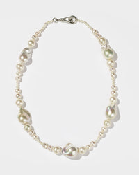 A sterling silver necklace featuring a strand of round and baroque freshwater pearls, with a silver clasp.
