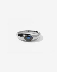 A sterling silver ring with a central oval cut ethical blue sapphire swiss set in a smooth, rounded band.