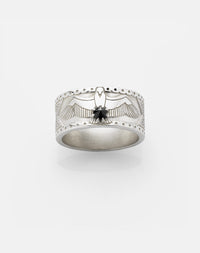 A sterling silver ring featuring a detailed eagle design with a round brilliant stone set in the center, surrounded by a pattern of a Russian orthodox cross and skull etched around the band.