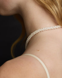 Pearl necklace worn by a person with a dark background