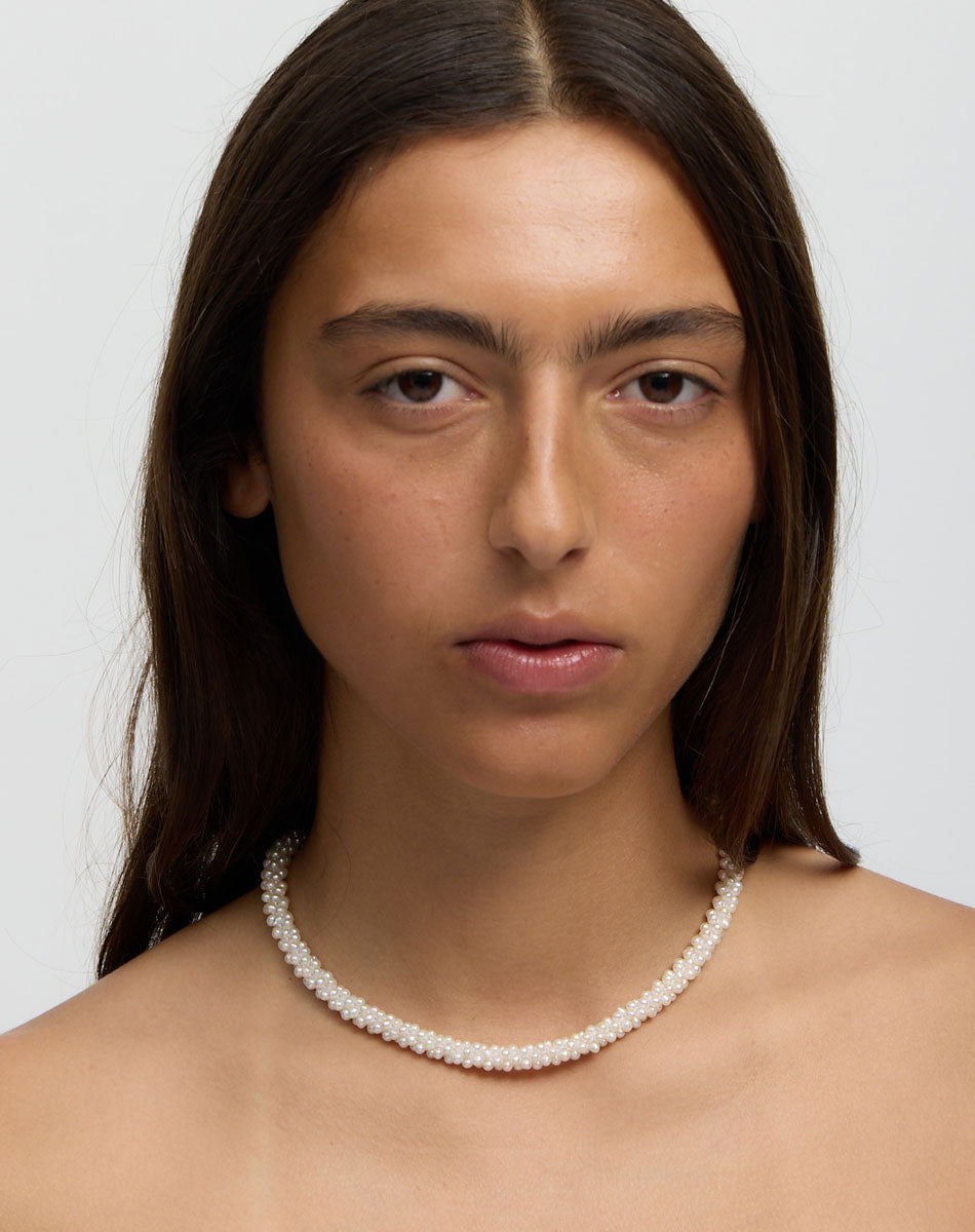 Woman wearing a pearl necklace against a plain background