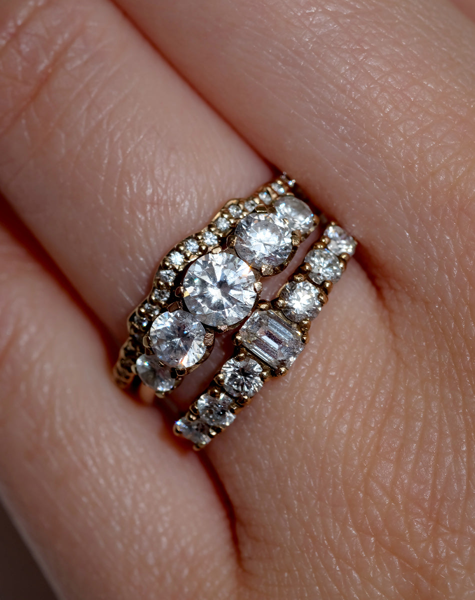 Three gold and diamond engagement and wedding rings on a hand.