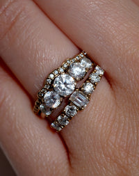 Three gold and diamond engagement and wedding rings on a hand.