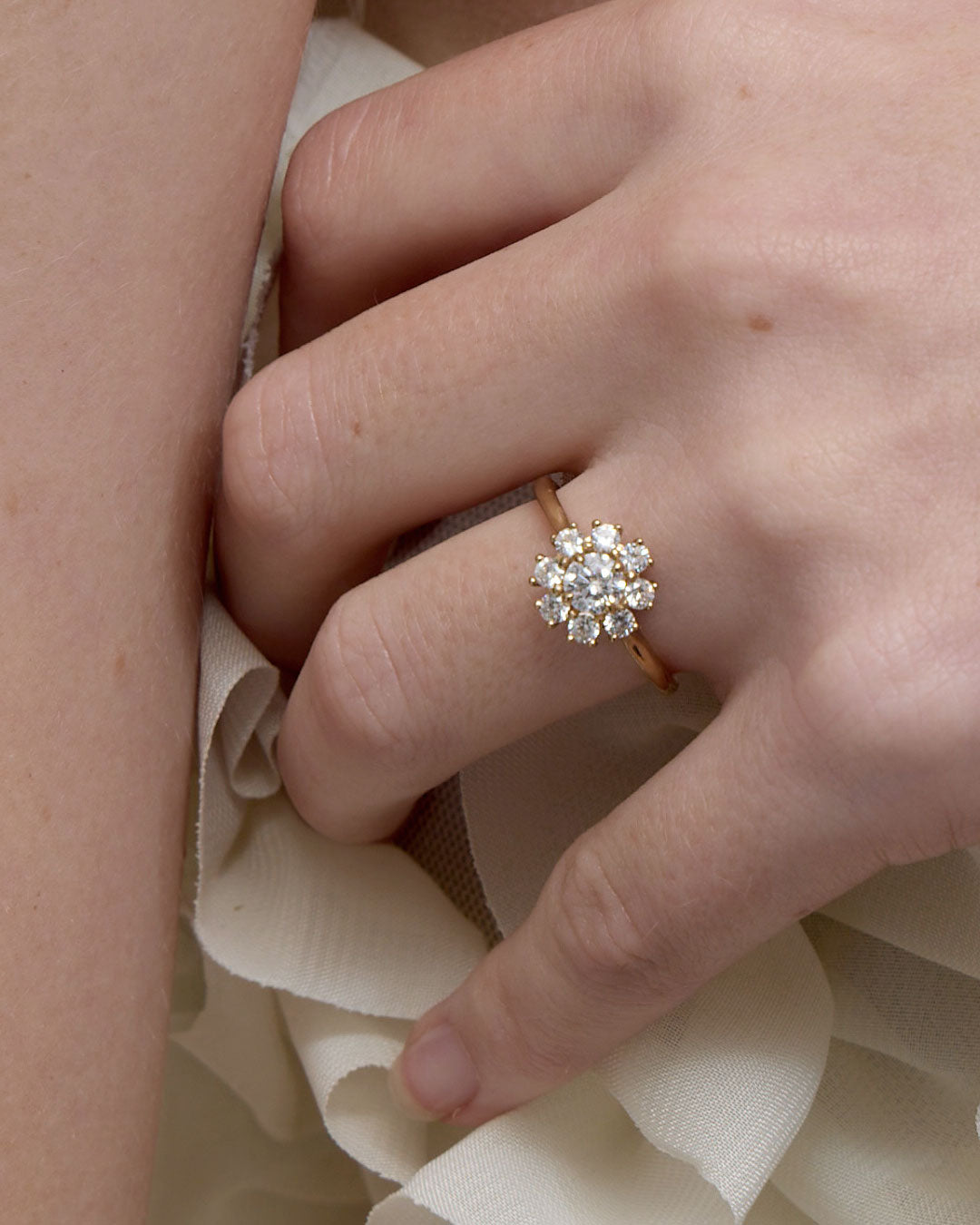 Close-up of a hand wearing a diamond ring on a soft fabric background