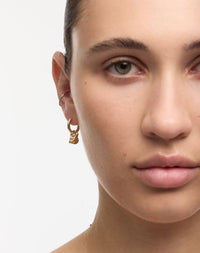 Close-up of a person wearing a gold cat earring 
