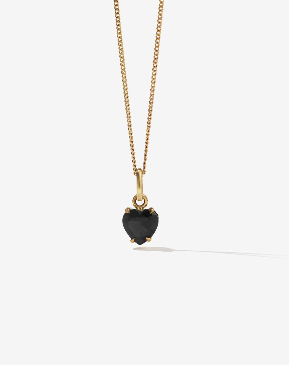 Gold necklace with a black onyx heart-shaped pendant on a white background