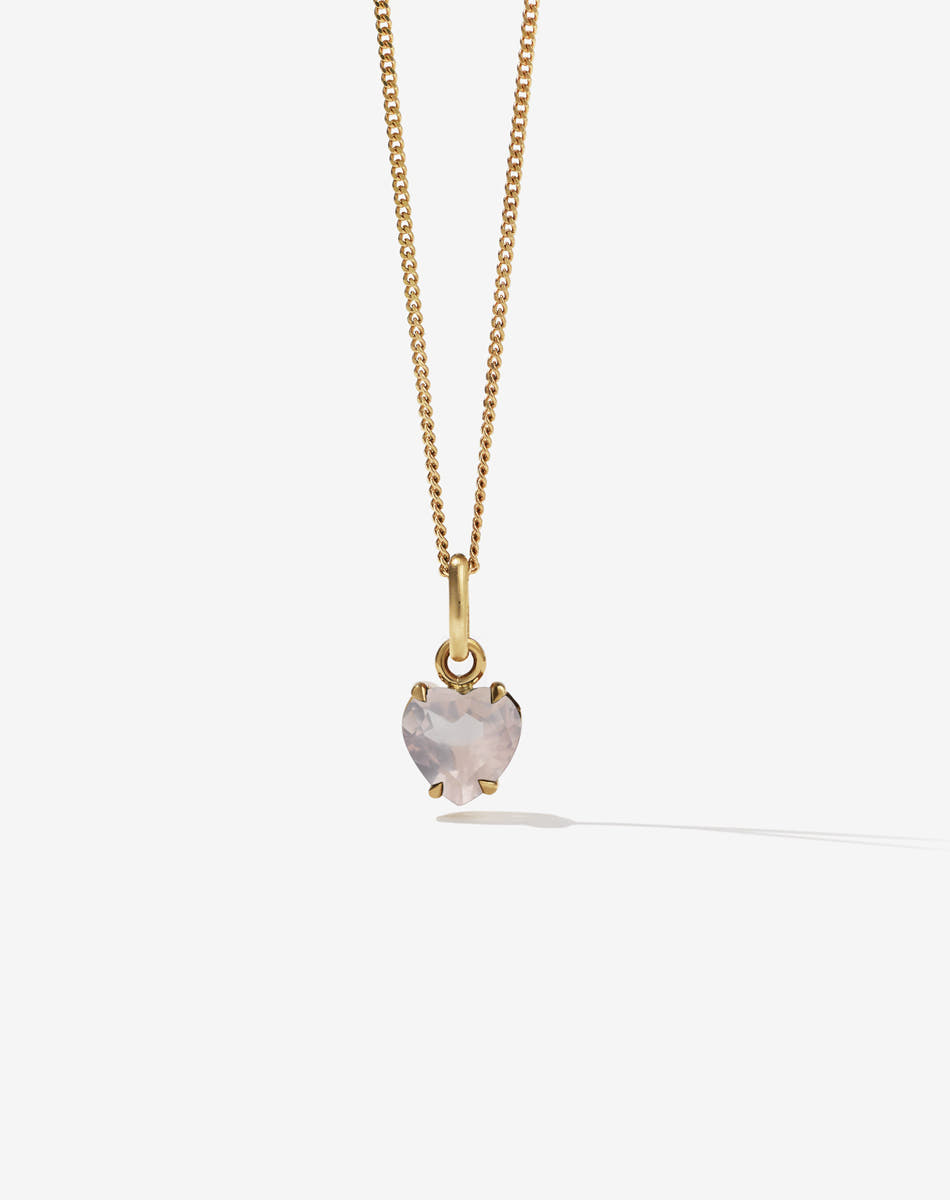 Gold necklace with a heart-shaped rose quartz pendant on a light gray background