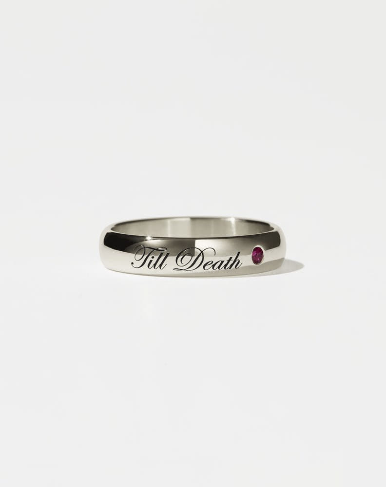 A 14ct white gold band ring with the phrase 'Till Death' engraved on it and a single ruby set in a white gold band.