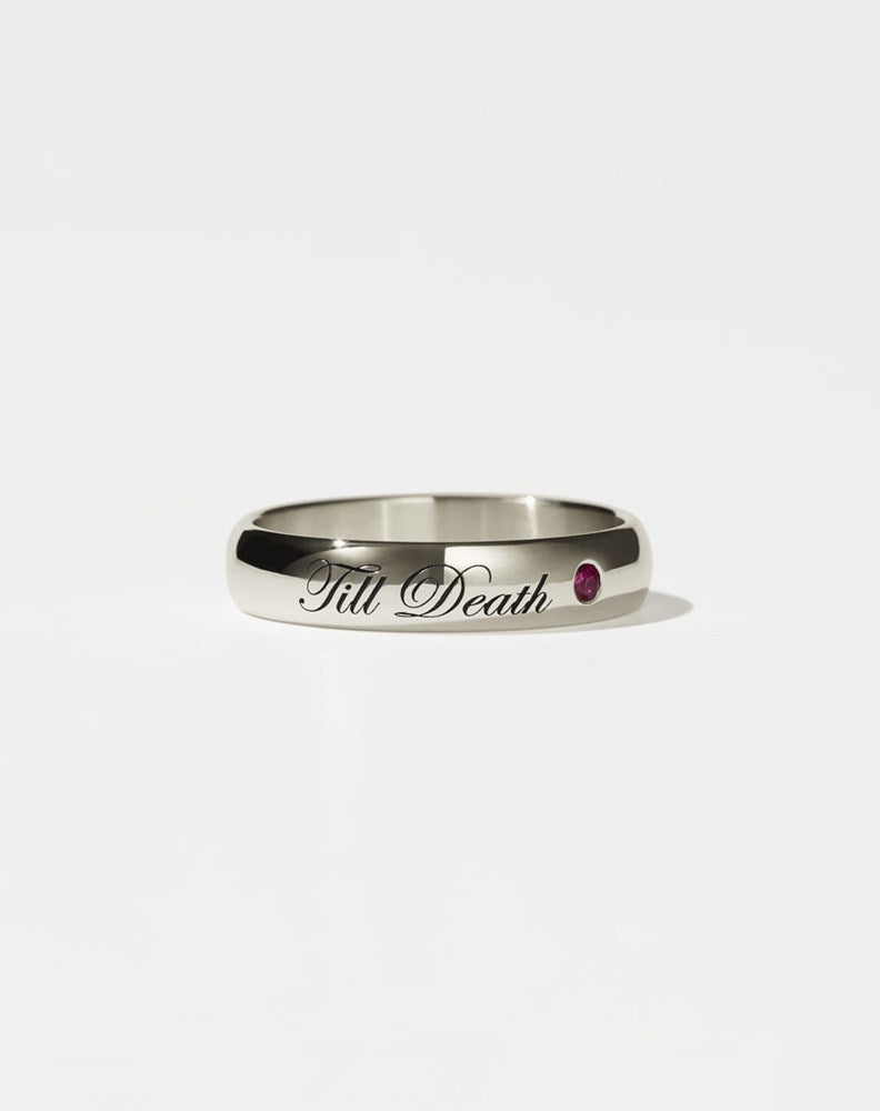 A 14ct white gold band ring with the phrase 'Till Death' engraved on it and a single ruby set in a white gold band.
