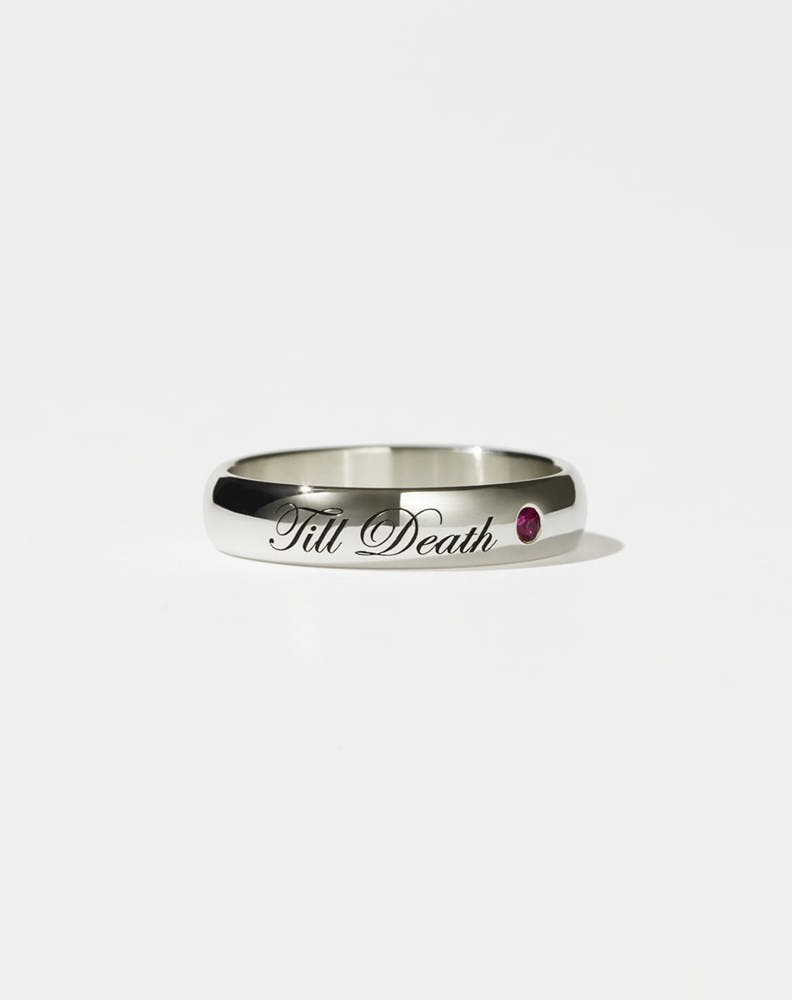 A sterling silver band ring with the phrase 'Till Death' engraved on it, featuring a small ruby on one side.