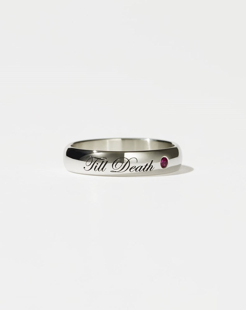 A sterling silver band ring with the phrase 'Till Death' engraved on it, featuring a small ruby on one side.