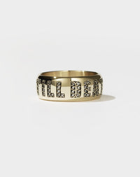 A cigar-style yellow gold band ring with 'Till Death' engraved on it and pave-set with diamonds.