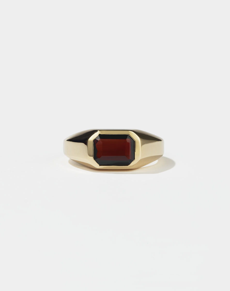 A gold ring with a red Garnet gemstone on a white background. Made by Meadowlark Jewellery in New Zealand.