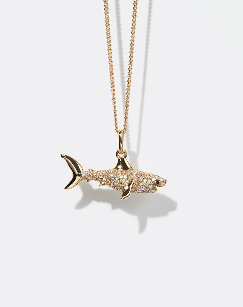 Gold shark pendant set with diamonds necklace on a white background