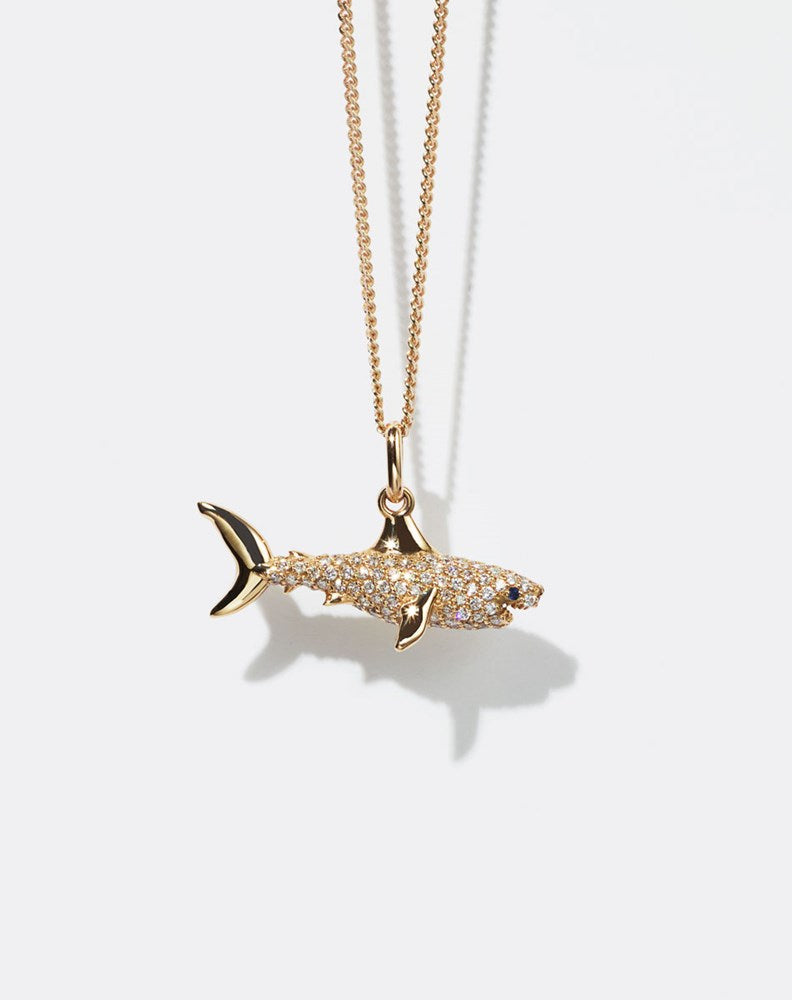 Gold shark pendant set with diamonds necklace on a white background