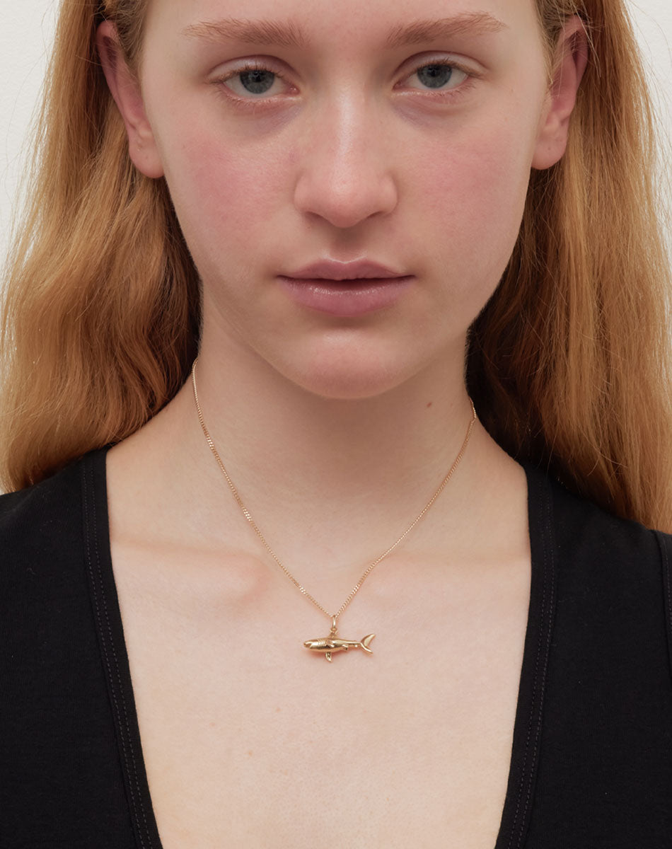 Gold shark charm necklace on a model