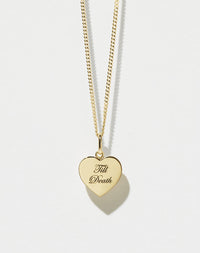 A gold fine chain necklace with a minimalist heart charm that reads 'Till Death'.