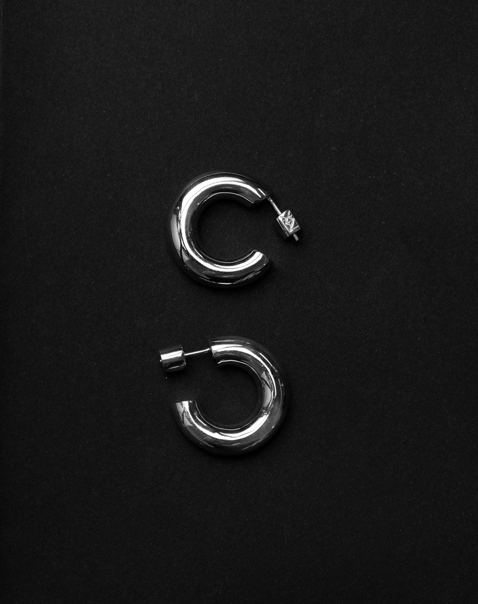 Pair of silver hoop earrings on a black background. 