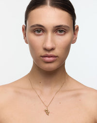 Woman wearing a gold necklace with a cherub charm.