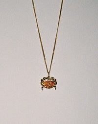 Gold necklace with a crab charm pendant set with red sapphires