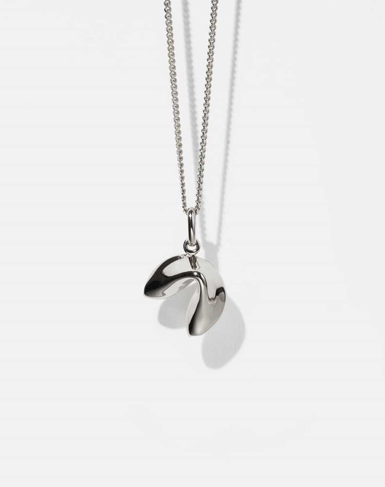 Silver necklace with fortune cookie shaped pendant on a white background