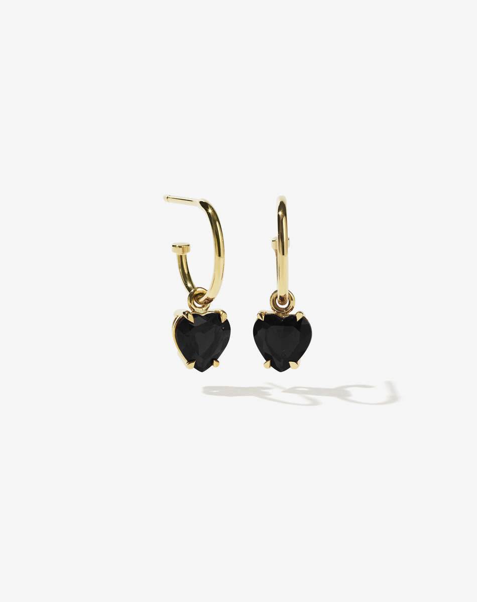 Gold heart-shaped earrings with black onyx stones on a white background