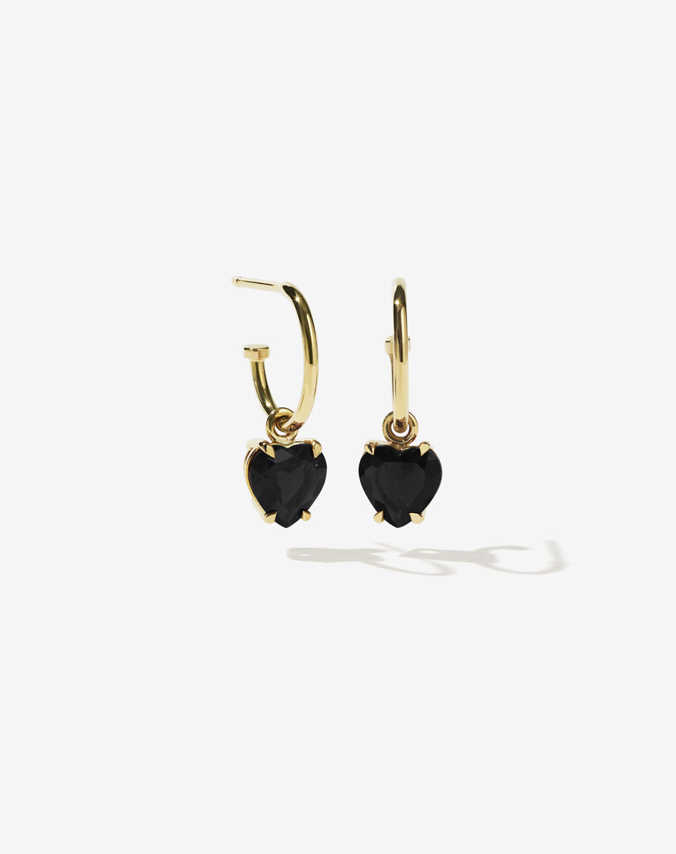 Gold heart-shaped earrings with black onyx stones on a white background