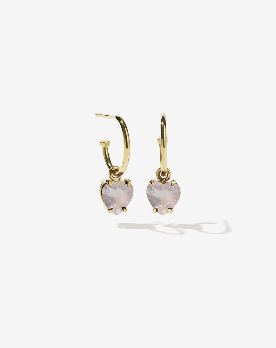 Gold hoop earrings with heart-shaped rose quartz pink gemstones on a white background