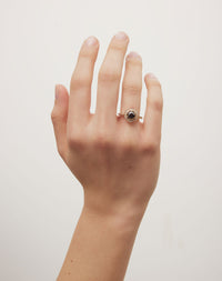 Black diamond engagement ring with hexagon halo on a hand.
