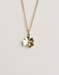Gold four-leaf clover necklace on a light grey background