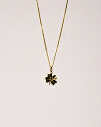 Gold necklace with a lucky four leaf clover pendant on a grey background