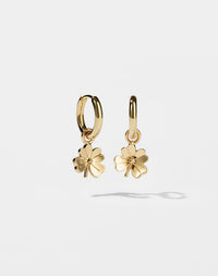Gold hoop earrings with for leaf clover charms on a light grey background