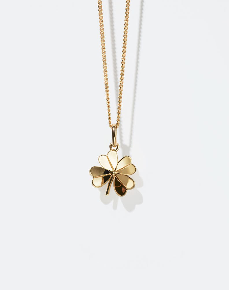 Gold necklace with a four-leaf clover pendant on a white background