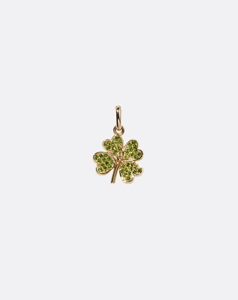 Gold four-leaf clover charm set with green gemstones on a white background