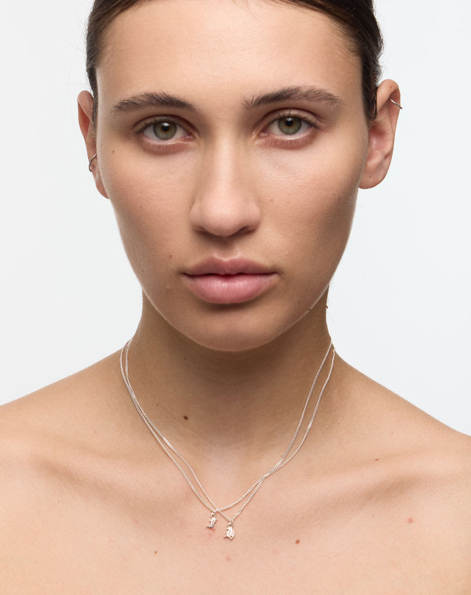 Woman wearing a delicate necklace with small letter or initial pendants 