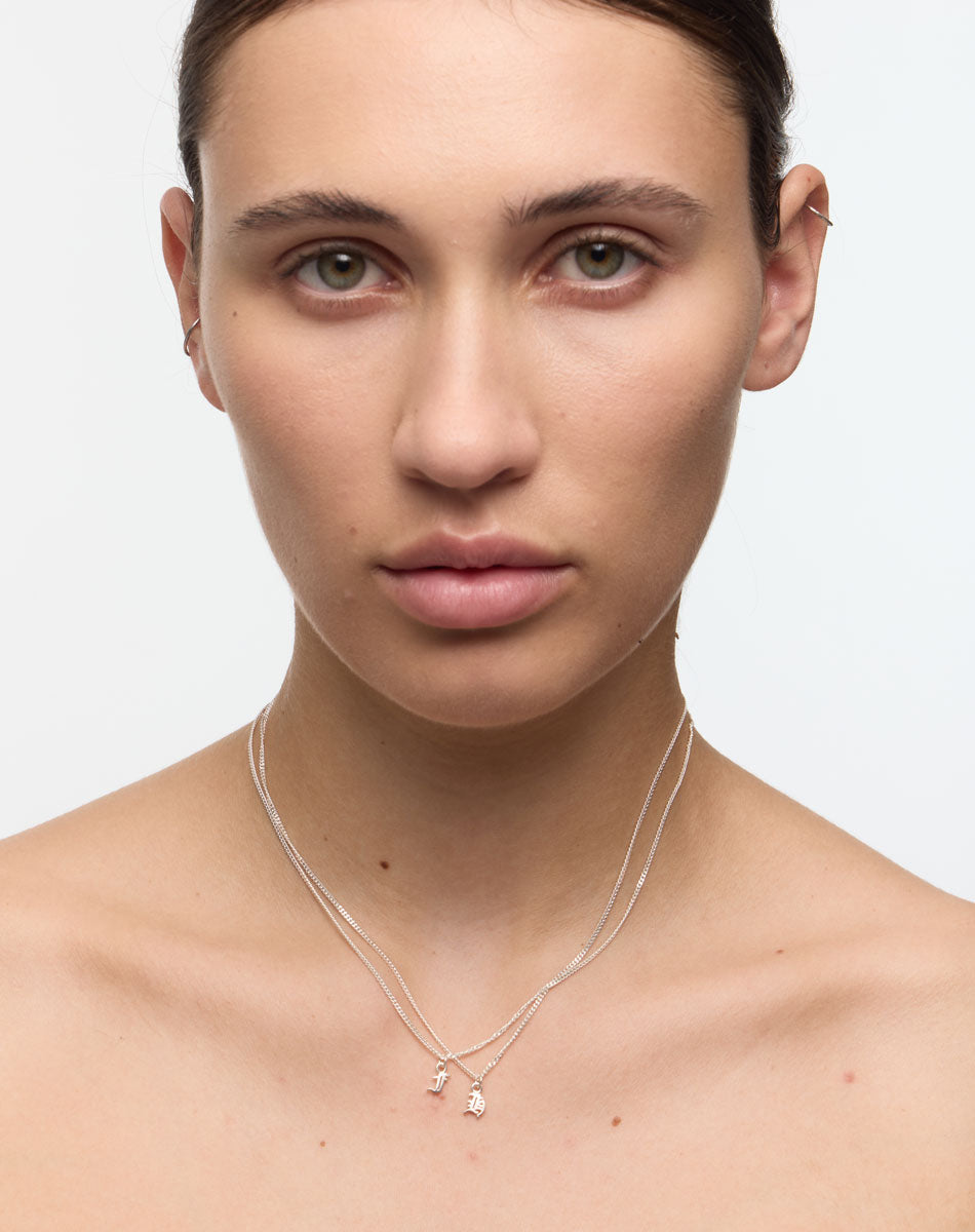 Woman wearing a delicate necklace with small letter or initial pendants 