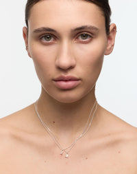 Woman wearing a delicate necklace with small letter or initial pendants 