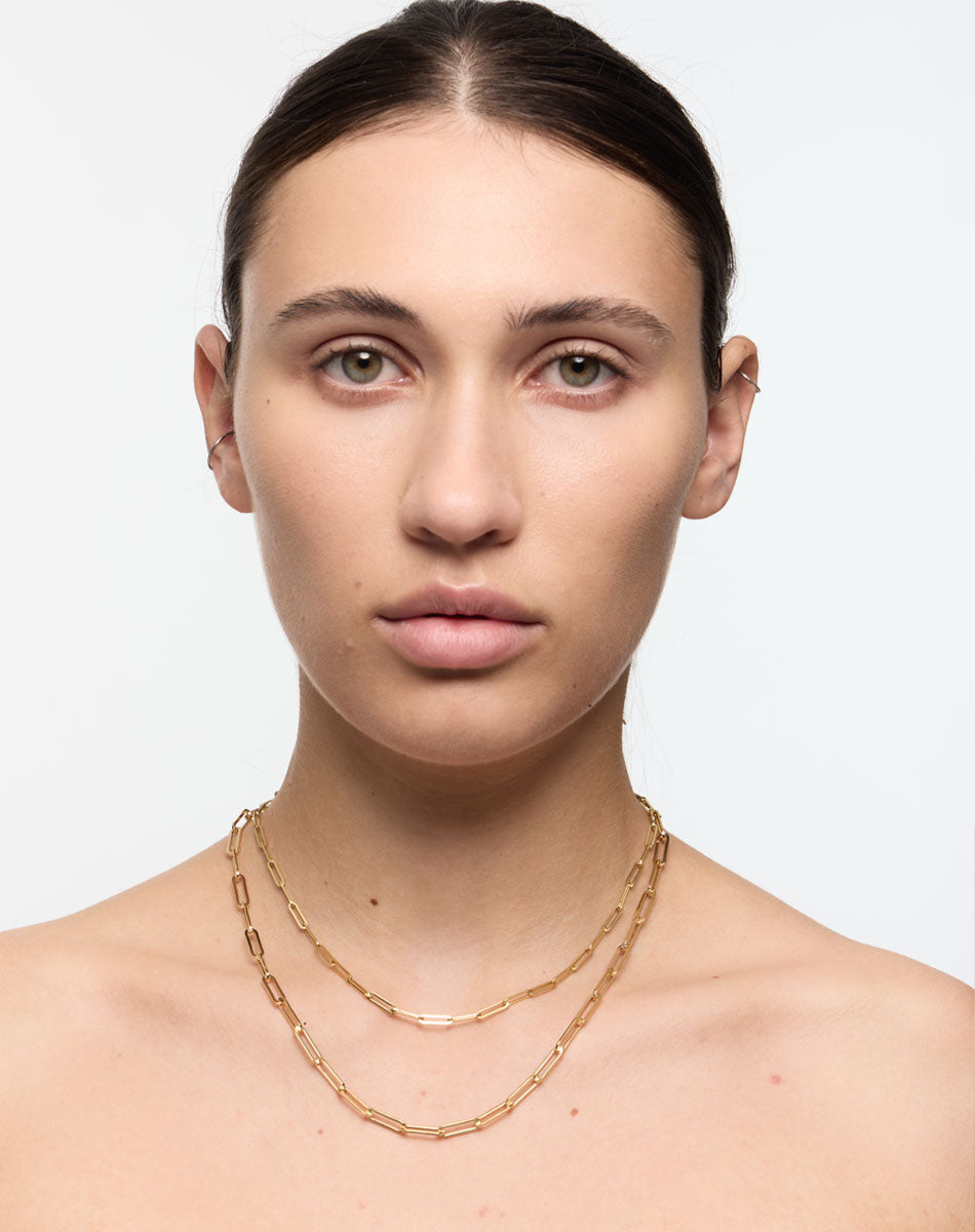 Gold paperclip chains fine and bold, worn on a model.