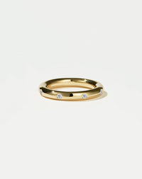 Gold ring with embedded diamonds on a light grey background