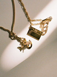 Gold necklace with charms on a light background