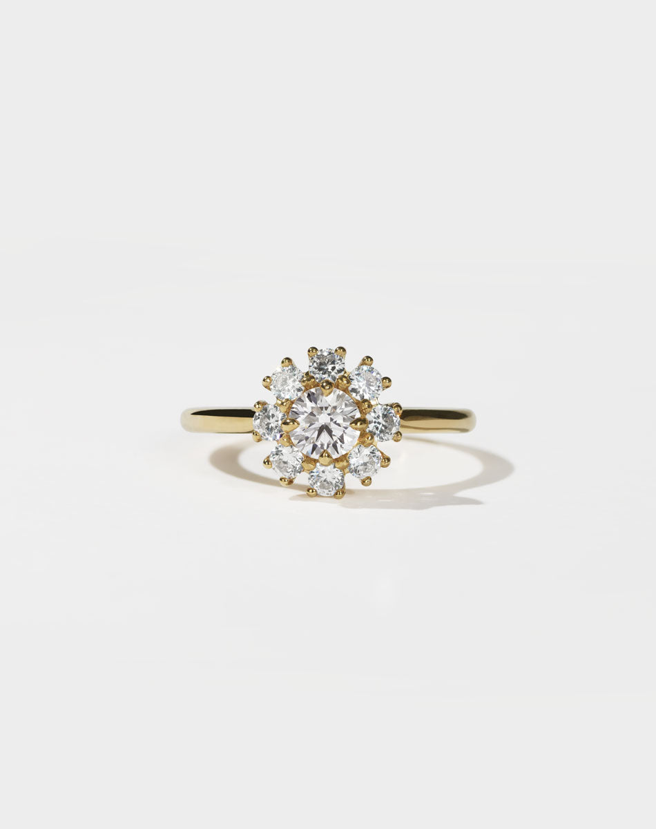Gold ring with a diamond cluster on a light gray background