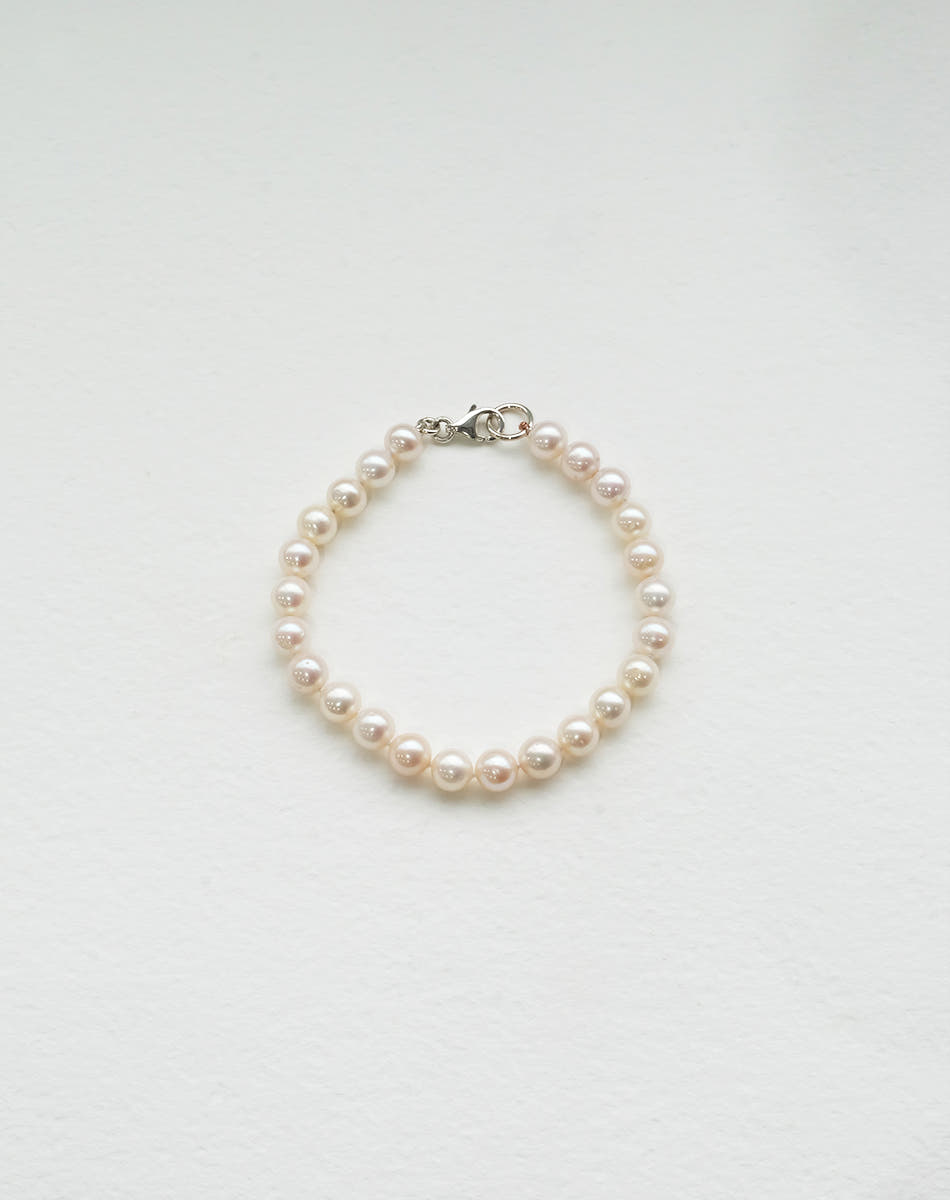 A bracelet featuring round freshwater pearls strung on silk thread with sterling silver clasp.