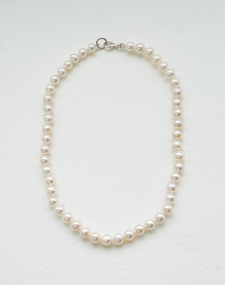 A freshwater pearl necklace with a classic round pearl design, strung on a silk thread and knotted.
